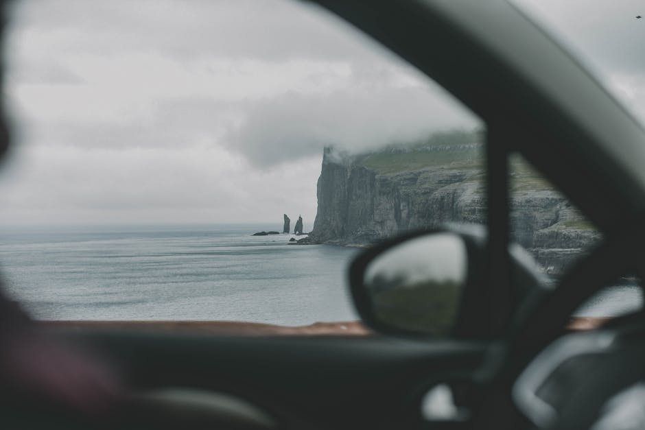 Scenic view of the Faroe Islands coastline through a car window, showcasing dramatic cliffs and ocean. — Photo de Diana Smykova sur Pexels